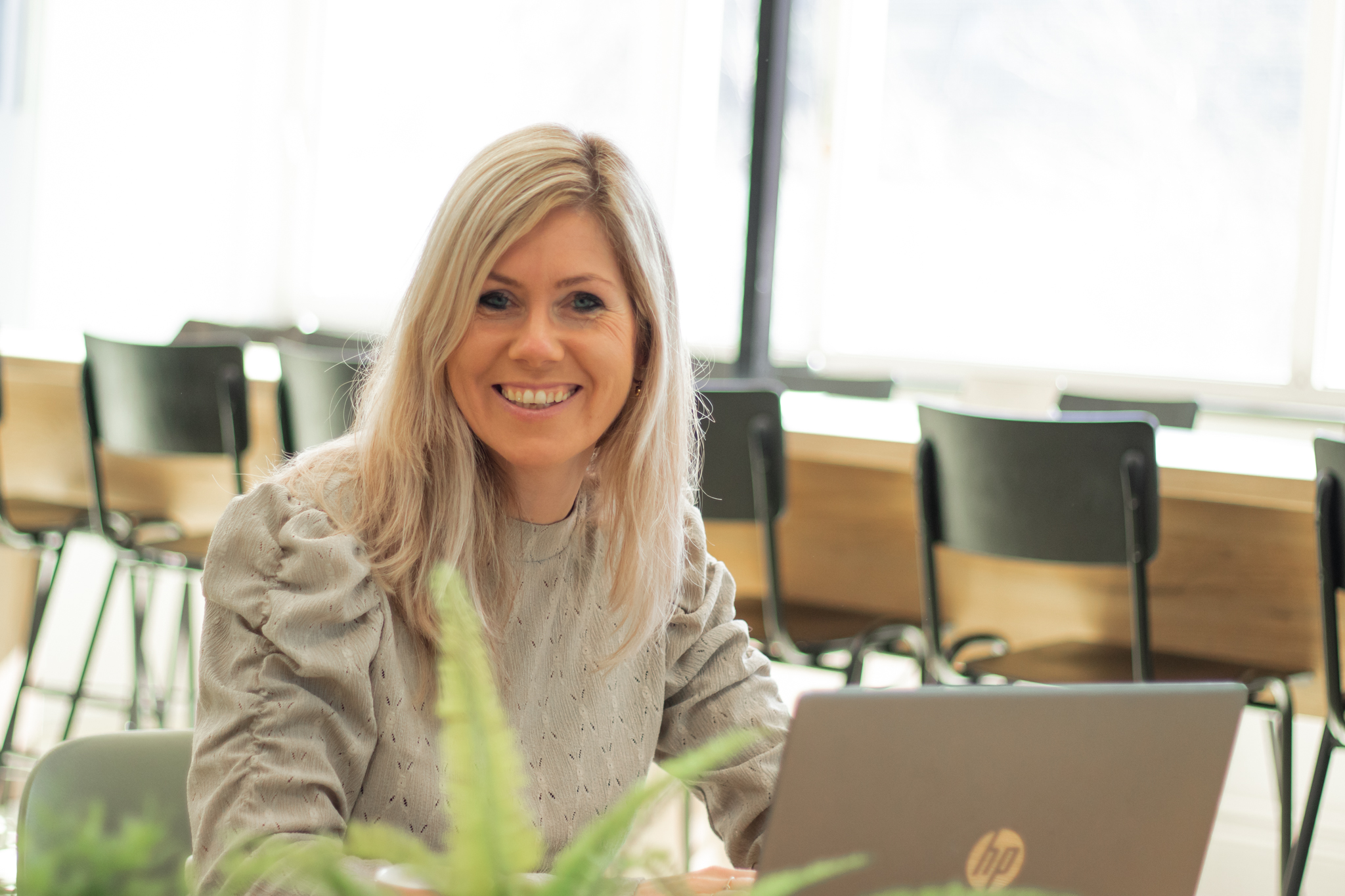 Jolijn van de Hoef aan tafel, kijkt recht in de camera – symbool voor leiderschap, reflectie en eigenaarschap in het onderwijs