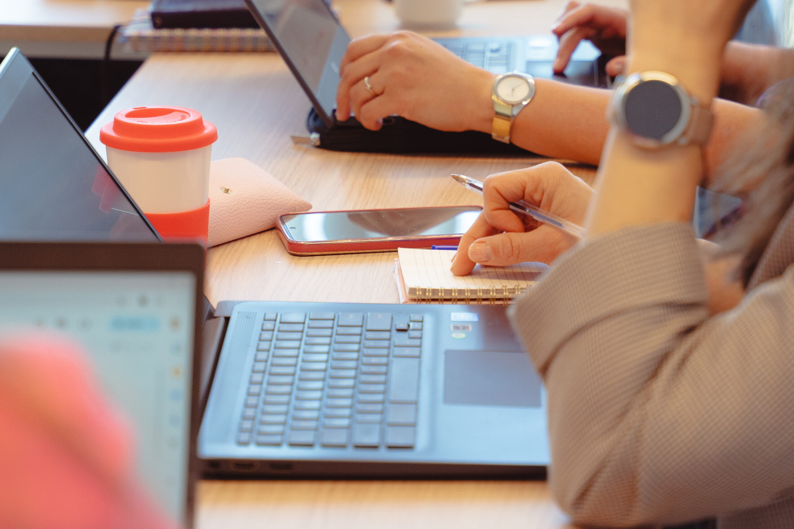 Teamleden werken samen rond tafel met werkboeken en laptop – illustratie van blended programma in het onderwijs