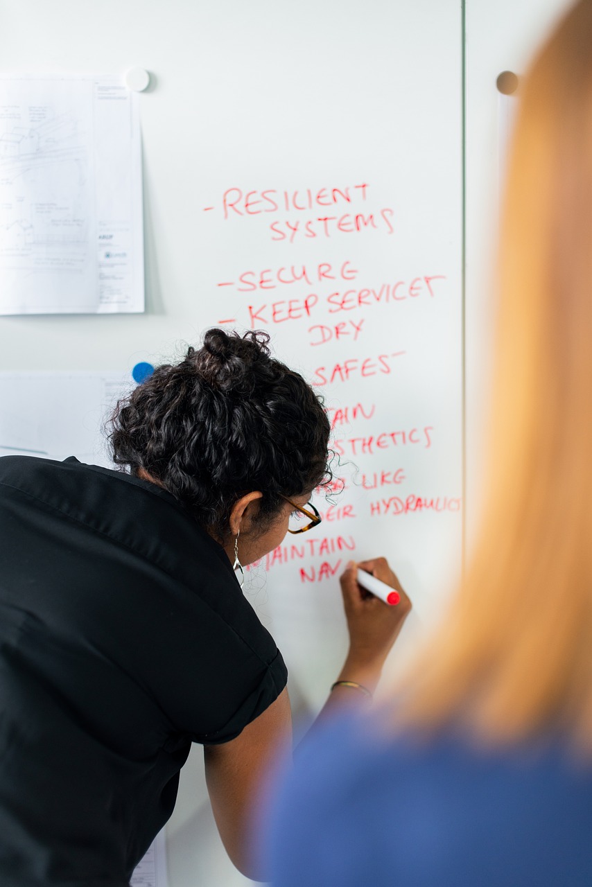 Vrouw schrijft op een whiteboard – symbool voor ieders bijdrage aan het gezamenlijke resultaat.